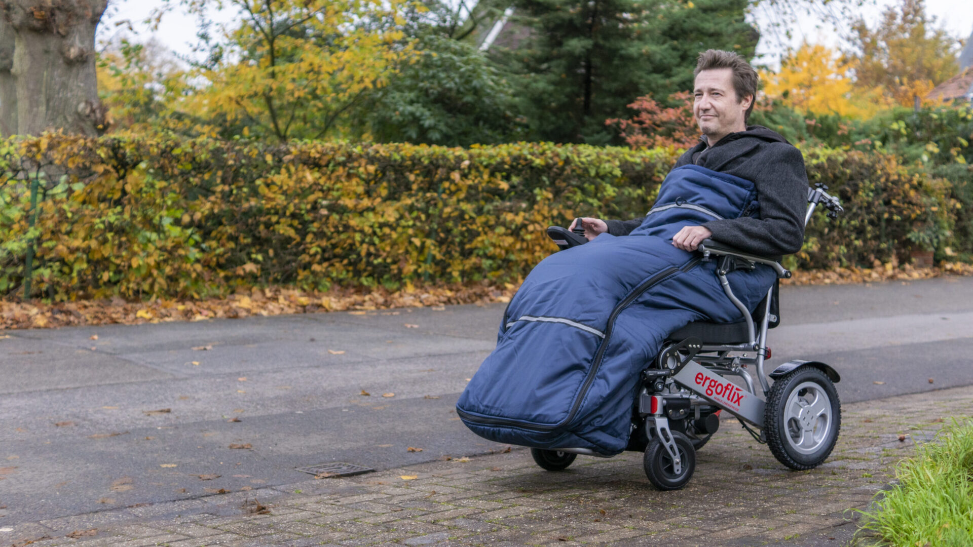 Mann in Elektrorollstuhl mit Rollstuhlschlupfsack