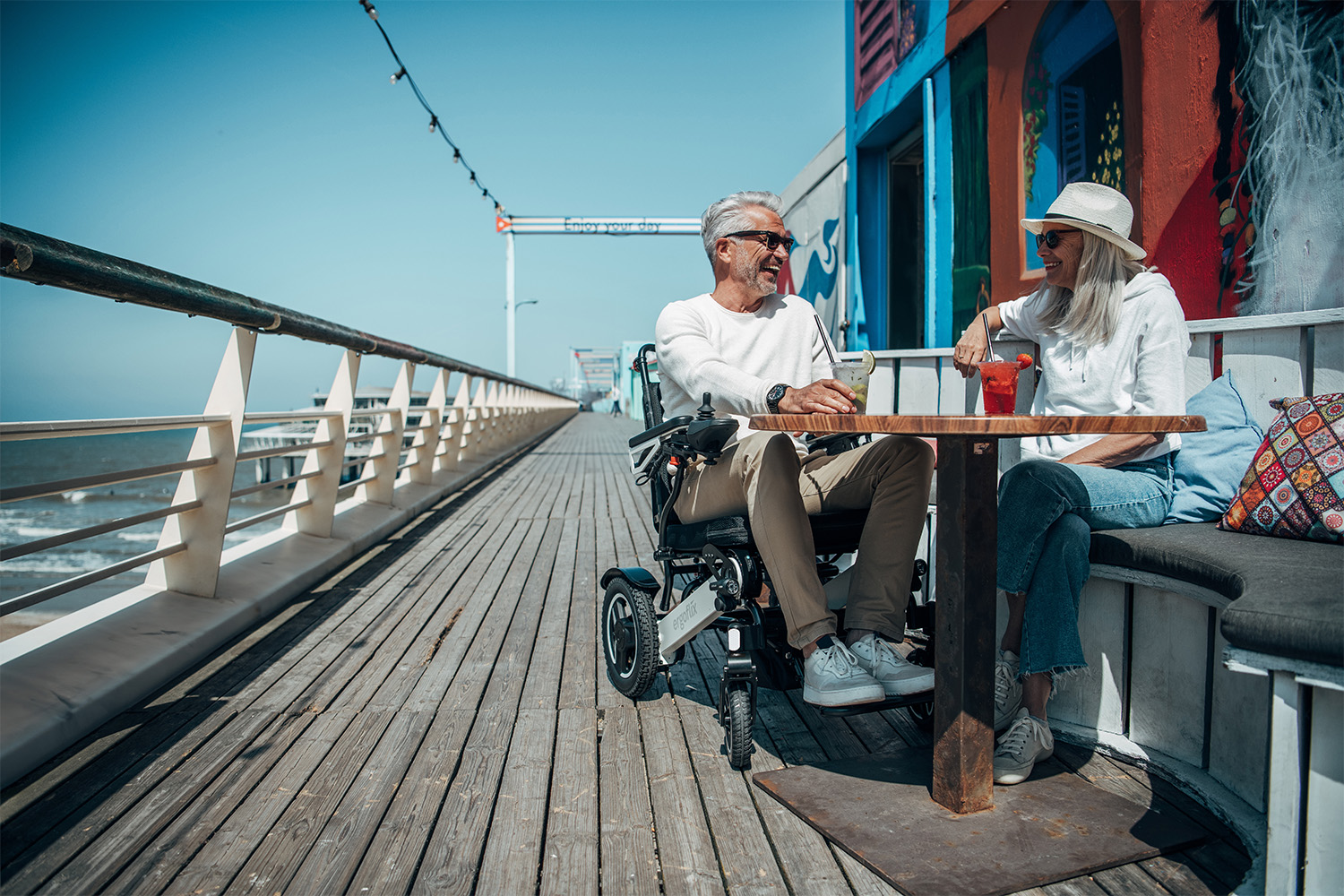 Dieses Bild zeigt eine Frau mit E-Rollstuhl und einen Mann im Restaurant