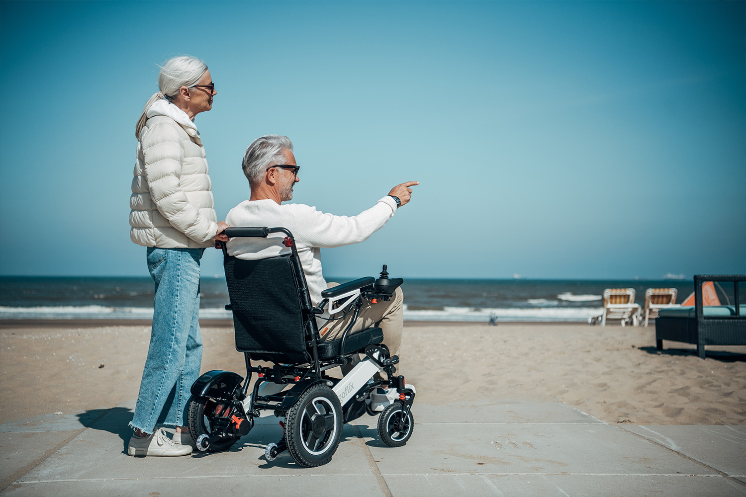 Dieses Bild zeigt einen Mann im Rollstuhl und seine Frau am Strand als Symbolbild für elektrische Rollstühle Preise