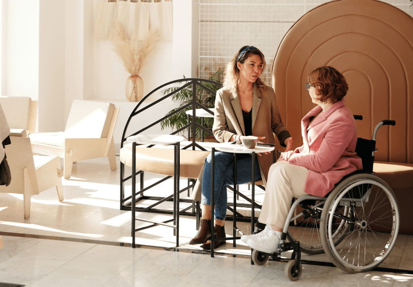 Rollstuhl Krankenkasse: Dieses Bild zeigt eine Mitarbeitern, die eine Rollstuhlfahrerin berät