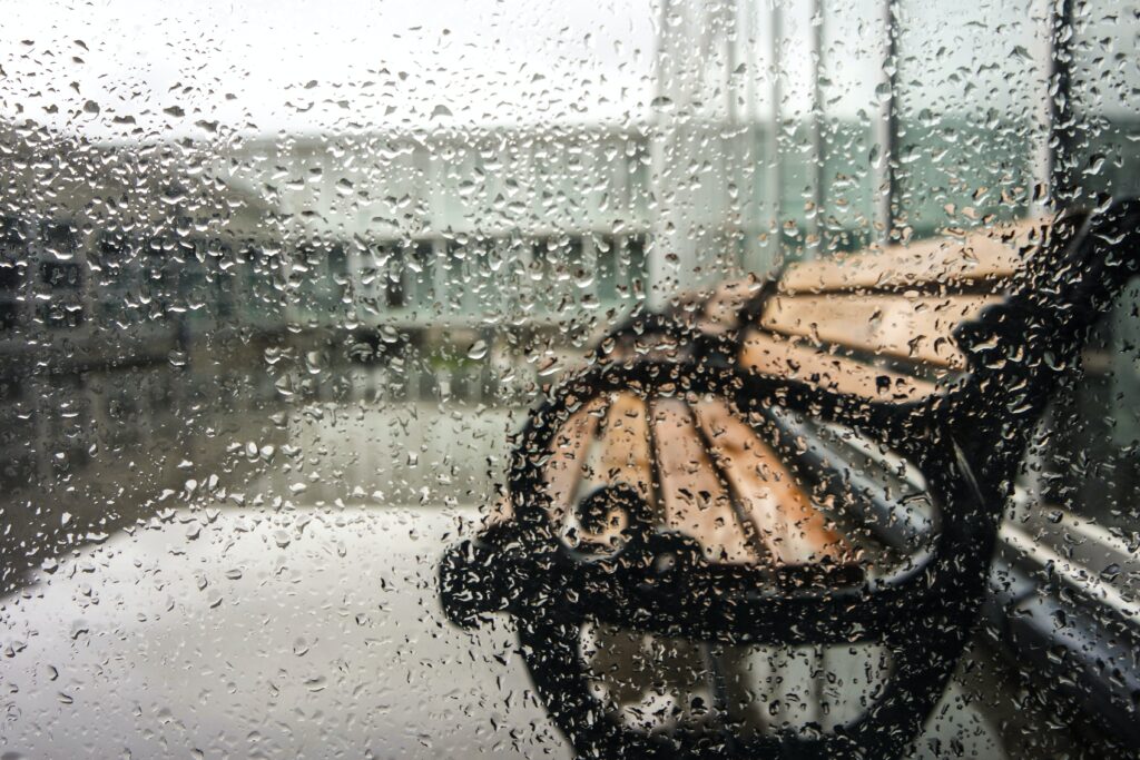 Dieses Bild zeigt eine Parkbank im Regen.