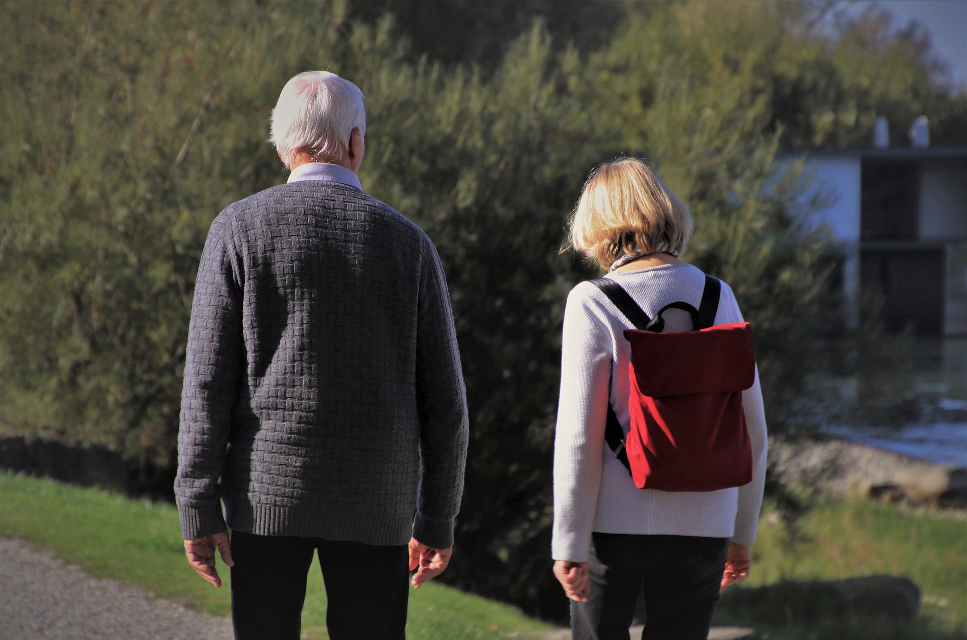 Dieses Bild zeigt zwei Senioren von hinten, die spazieren gehen.
